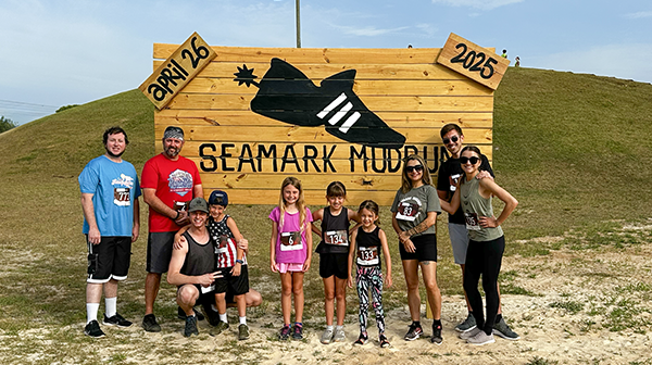 A group of adults and children standing outside in front of event signage